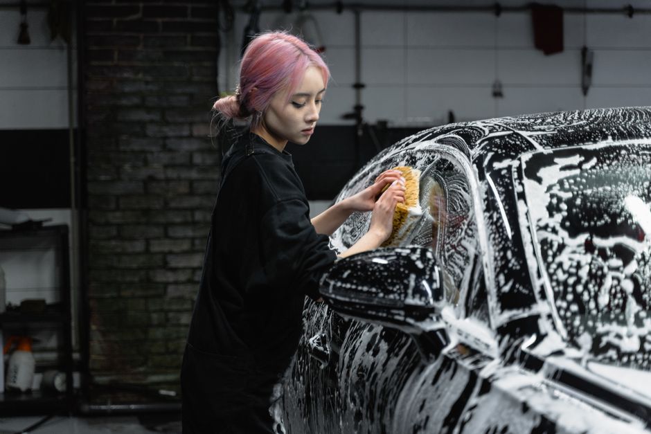 Friendly car wash worker smiling while cleaning a vehicle